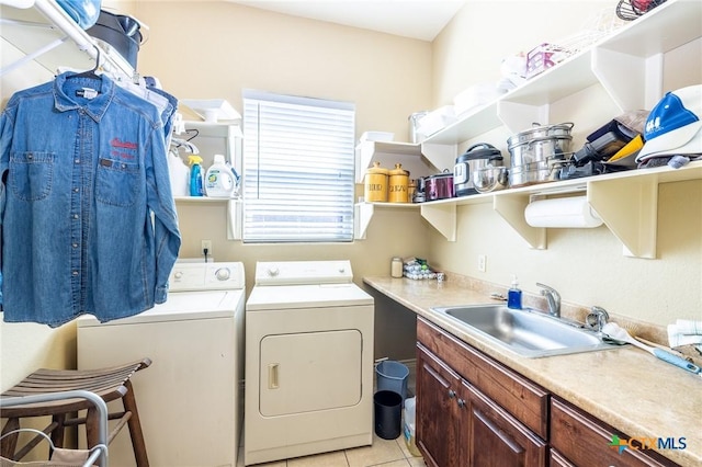 clothes washing area featuring a sink, light tile patterned floors, cabinet space, and washing machine and dryer