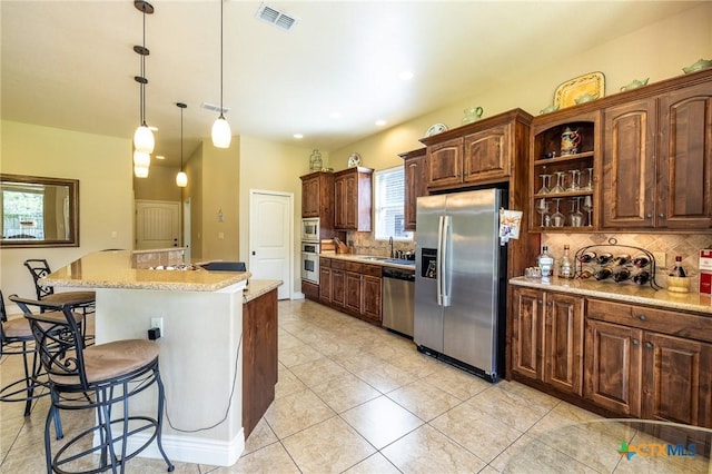 kitchen with tasteful backsplash, a breakfast bar area, stainless steel appliances, a sink, and visible vents