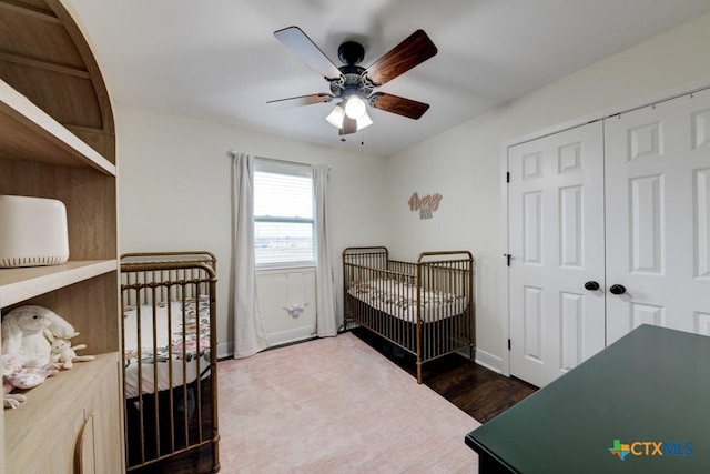 bedroom featuring a crib, ceiling fan, and a closet