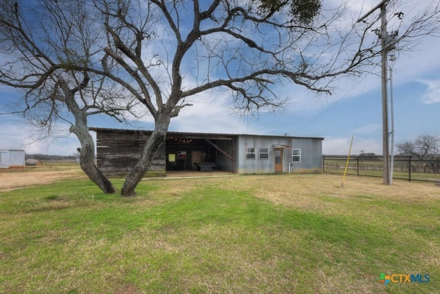 back of property featuring an outdoor structure and a lawn