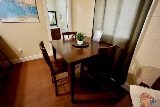 dining room featuring concrete block wall and baseboards