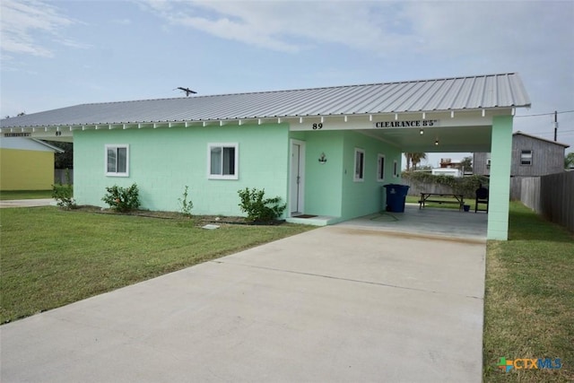 view of front of home featuring concrete block siding, a carport, a front lawn, and metal roof