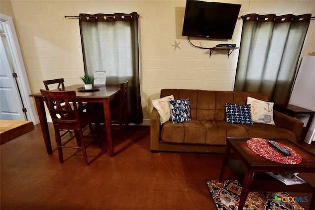 living area with finished concrete flooring and concrete block wall