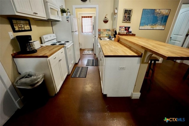 kitchen featuring a breakfast bar, white appliances, wooden counters, and a sink