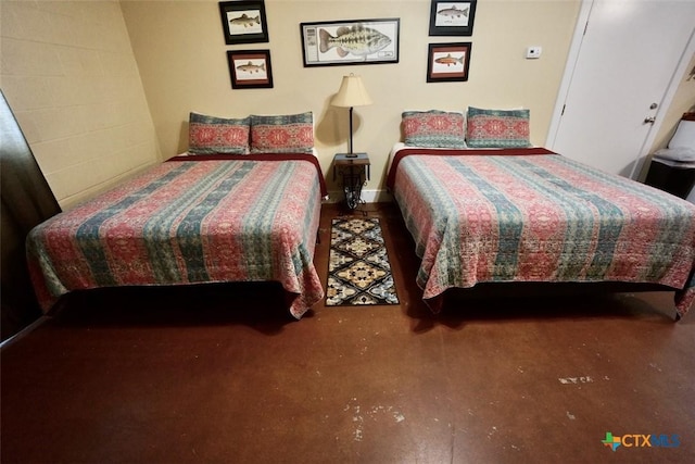 bedroom featuring concrete block wall