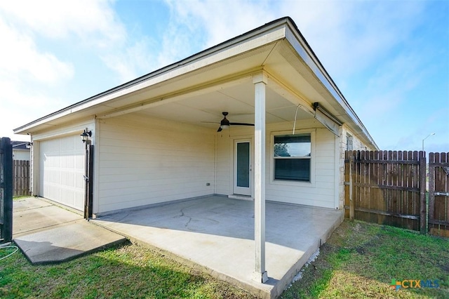 exterior space featuring a garage, a ceiling fan, a patio area, and fence