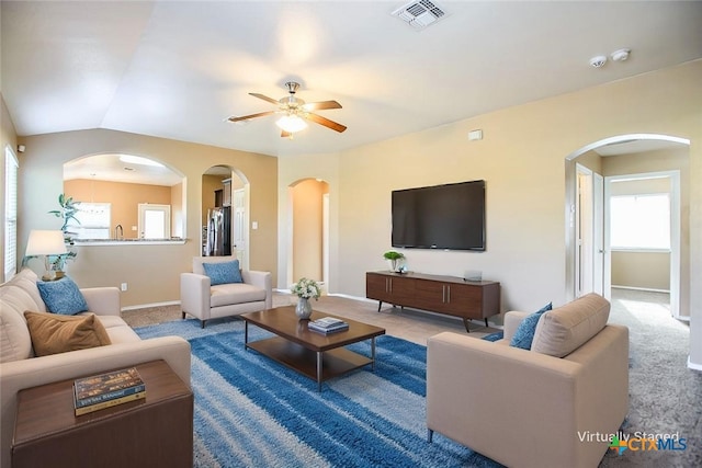 living area featuring baseboards, a ceiling fan, visible vents, and arched walkways