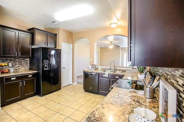 kitchen with arched walkways, a sink, backsplash, black appliances, and light tile patterned floors