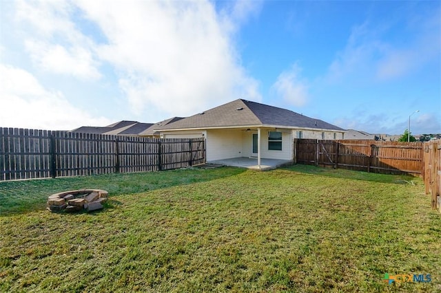 rear view of property featuring a fire pit, a patio, a fenced backyard, and a lawn