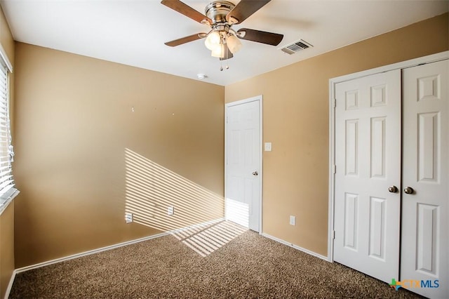 unfurnished bedroom with baseboards, carpet floors, ceiling fan, and a closet