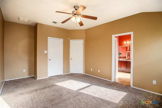 unfurnished bedroom featuring baseboards, visible vents, light colored carpet, and connected bathroom