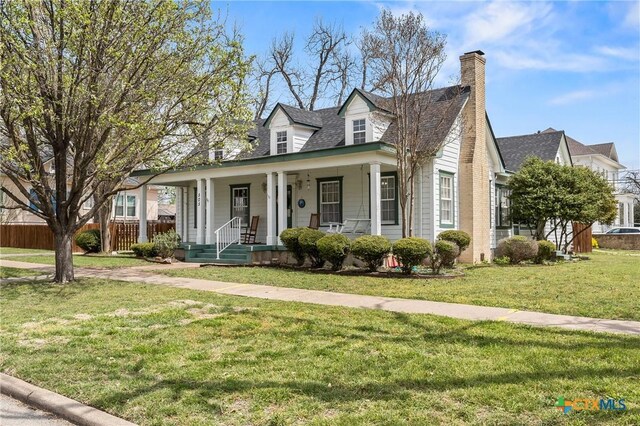 505 N 7th St, Temple, TX 76501 - cape cod-style house with a chimney, covered porch, fence, and a front lawn