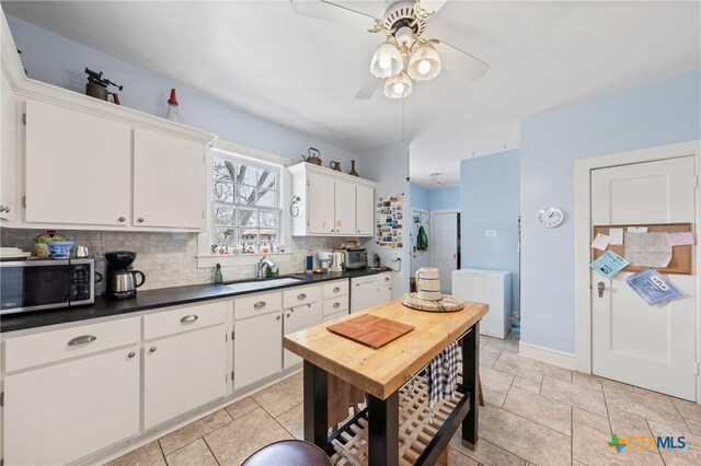 505 N 7th St, Temple, TX 76501 - kitchen featuring ceiling fan, tasteful backsplash, stainless steel microwave, a sink, and dark countertops