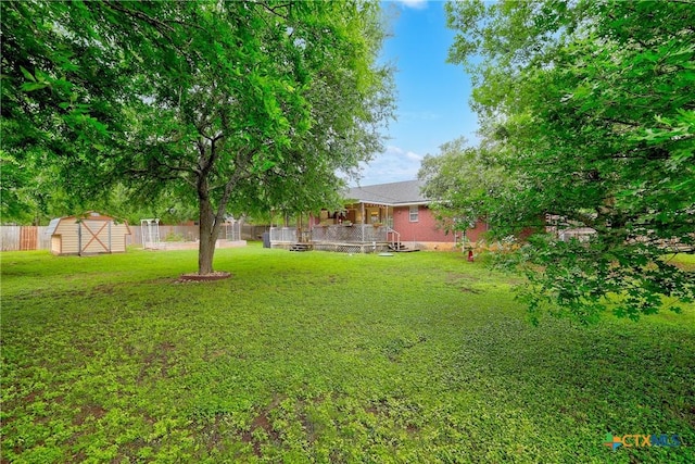 view of yard featuring a storage shed, fence, and an outbuilding