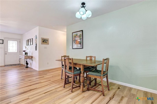 dining space with baseboards and light wood-style flooring