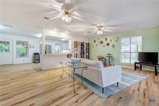living room with a ceiling fan, light wood-style flooring, and visible vents