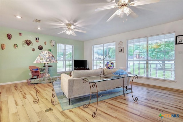 living area with baseboards, a ceiling fan, wood finished floors, and visible vents