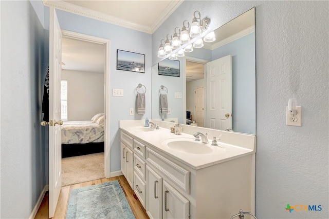 ensuite bathroom with crown molding, double vanity, wood finished floors, a sink, and ensuite bath