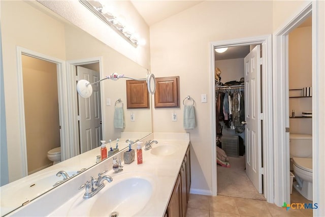 full bath featuring a sink, toilet, double vanity, and tile patterned floors