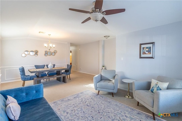 living room with visible vents, a wainscoted wall, ceiling fan with notable chandelier, carpet floors, and crown molding