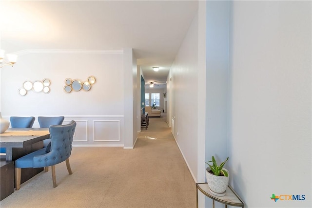 dining space with a decorative wall, ornamental molding, carpet, and a wainscoted wall