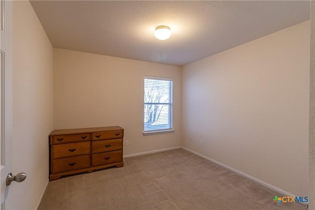 spare room featuring baseboards and light carpet