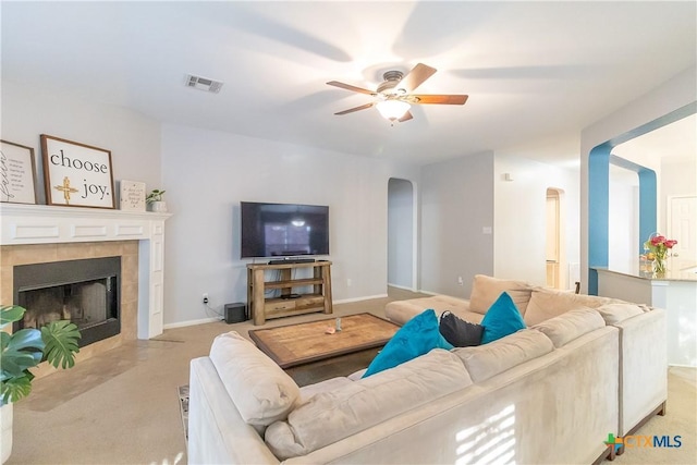 living room featuring arched walkways, visible vents, light carpet, and ceiling fan