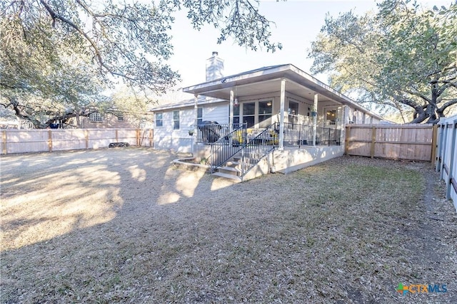 back of property with a porch, a chimney, and a fenced backyard