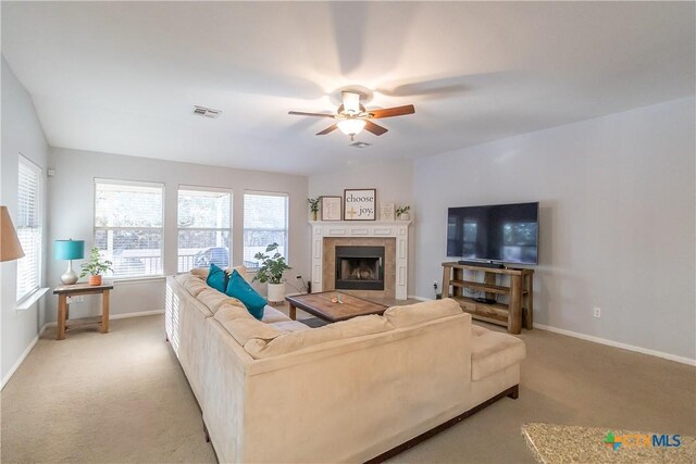 living room with visible vents, baseboards, light colored carpet, ceiling fan, and a tile fireplace