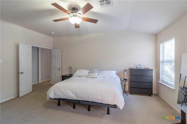 bedroom with a ceiling fan, visible vents, baseboards, vaulted ceiling, and light colored carpet