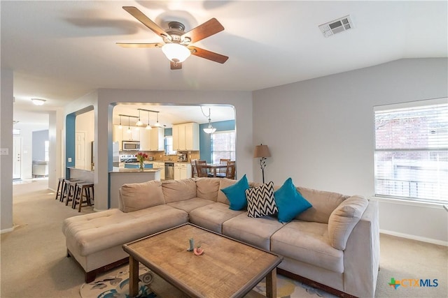 living area featuring baseboards, light colored carpet, visible vents, and ceiling fan