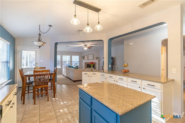 kitchen with visible vents, arched walkways, ceiling fan, open floor plan, and a center island