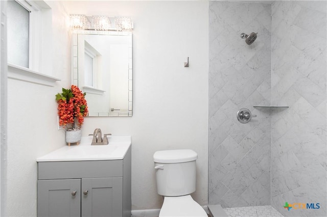 full bath featuring a tile shower, toilet, and vanity