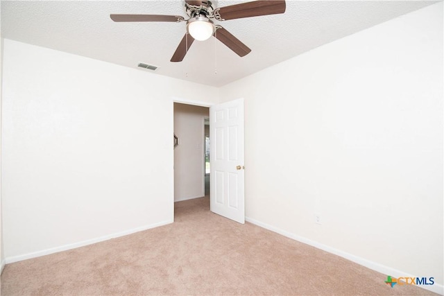 unfurnished room with ceiling fan, light carpet, visible vents, and baseboards