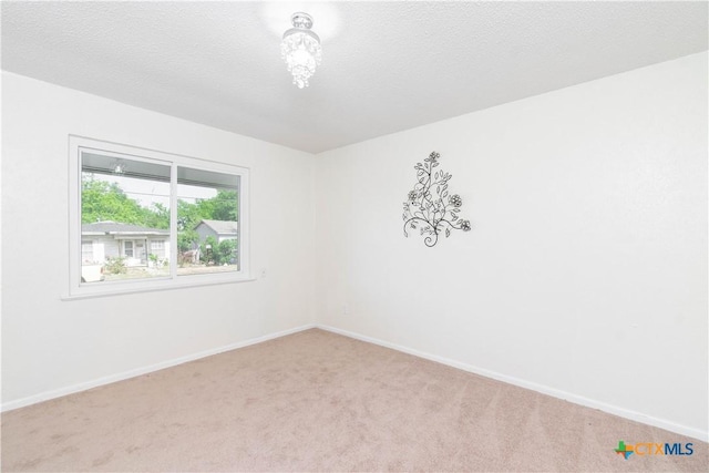 empty room with light carpet, baseboards, and a textured ceiling