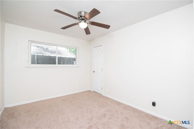 empty room with a textured ceiling, carpet flooring, baseboards, and a ceiling fan