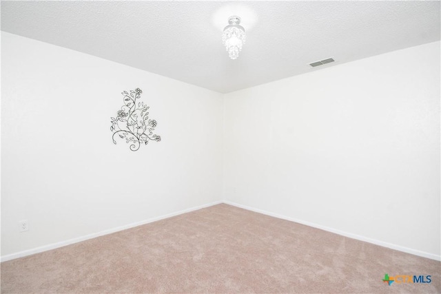 carpeted empty room featuring visible vents, baseboards, and a textured ceiling