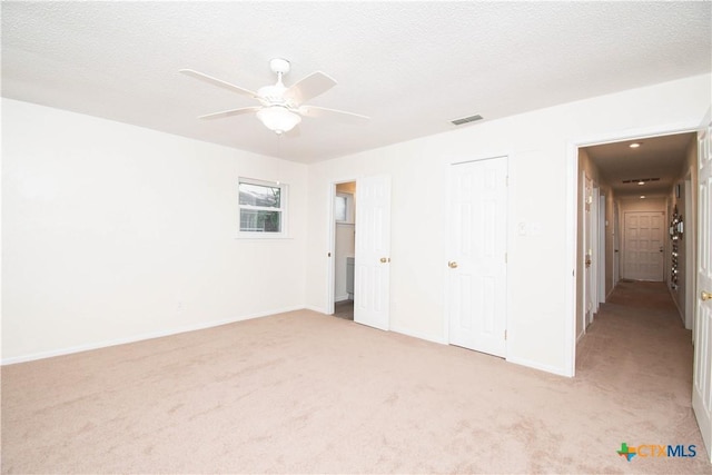 unfurnished bedroom featuring visible vents, a ceiling fan, baseboards, a textured ceiling, and light colored carpet