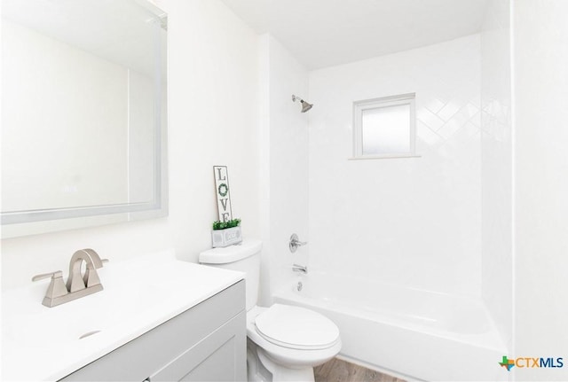 full bath featuring wood finished floors, toilet, vanity, and washtub / shower combination