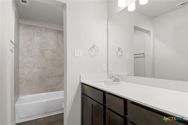 bathroom with hardwood / wood-style flooring, vanity, and tiled shower / bath combo