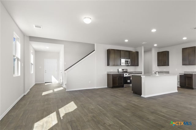 kitchen featuring dark hardwood / wood-style flooring, a center island with sink, and appliances with stainless steel finishes