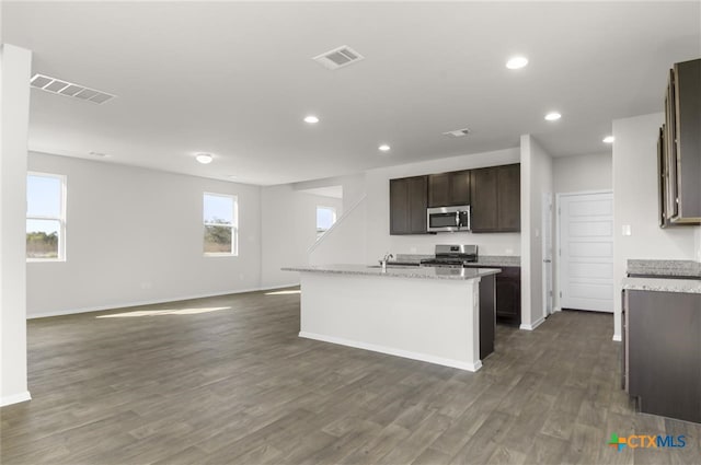 kitchen with a center island with sink, sink, dark hardwood / wood-style floors, appliances with stainless steel finishes, and dark brown cabinets