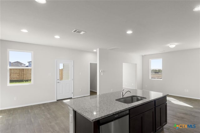 kitchen featuring light stone counters, a kitchen island with sink, sink, hardwood / wood-style flooring, and dishwasher