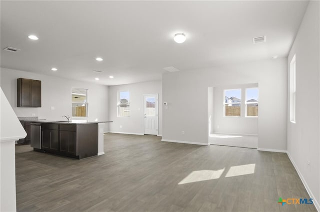 kitchen featuring dark hardwood / wood-style flooring, dark brown cabinetry, a kitchen island with sink, sink, and dishwasher