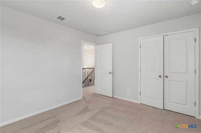 unfurnished bedroom featuring light colored carpet and a closet