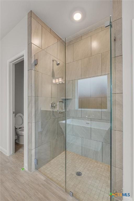 bathroom featuring toilet, an enclosed shower, and hardwood / wood-style flooring