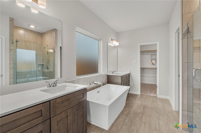 bathroom with wood-type flooring, vanity, and independent shower and bath