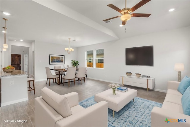 living room with vaulted ceiling, ceiling fan with notable chandelier, and light hardwood / wood-style flooring