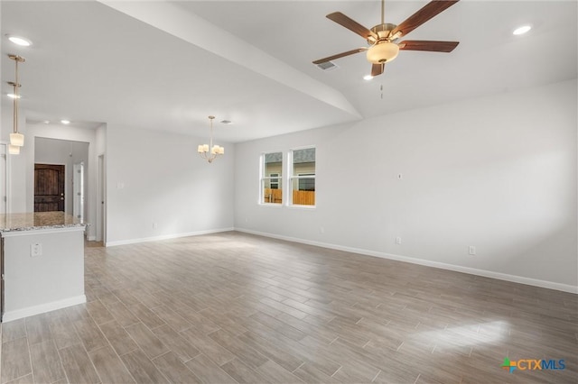 unfurnished living room with vaulted ceiling and ceiling fan with notable chandelier