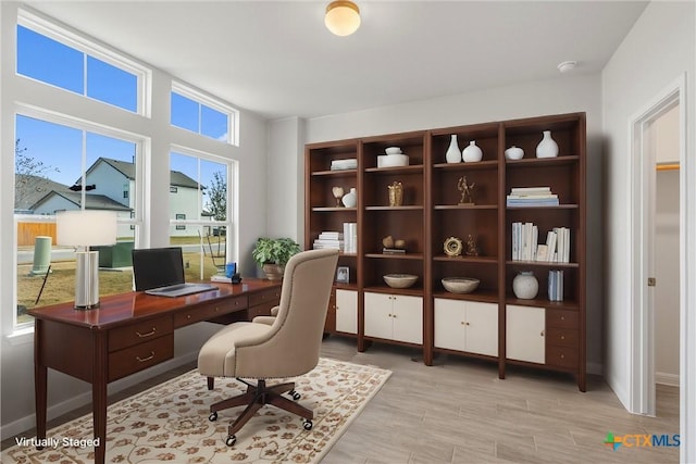 home office with light wood-type flooring and a wealth of natural light